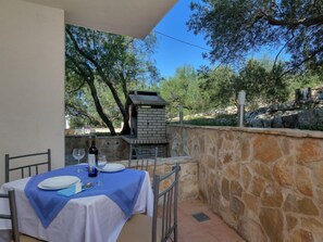 A table set for dining with a stone wall and a brick oven in the background. - Apartment Cico by Interhome (Hvar/Pokrivenik)