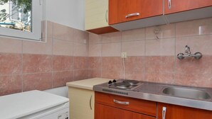 A compact kitchen with a gas stove, a sink, and wooden cabinets. - Apartment Cico by Interhome (Hvar/Pokrivenik)