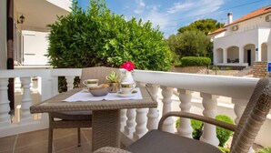 A balcony with wicker furniture, a table with a vase and a bowl, and a white railing. - Aquanur by Interhome (Vodice/Tribunj)