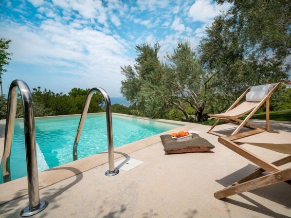 A poolside area with a lounge chair and a fruit bowl.
