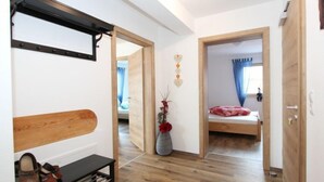 A bedroom with a wooden bed, a bedside table, a bench, and a vase with flowers. - Wildbachl by Interhome (Aschau im Zillertal)