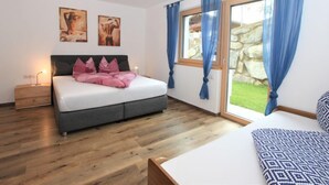 A bedroom with a bed, a nightstand, a window with curtains, and artwork on the wall. - Wildbachl by Interhome (Aschau im Zillertal)