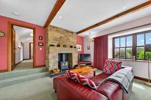 A cozy living room with a stone fireplace, a television, a sofa, and a window with a view.