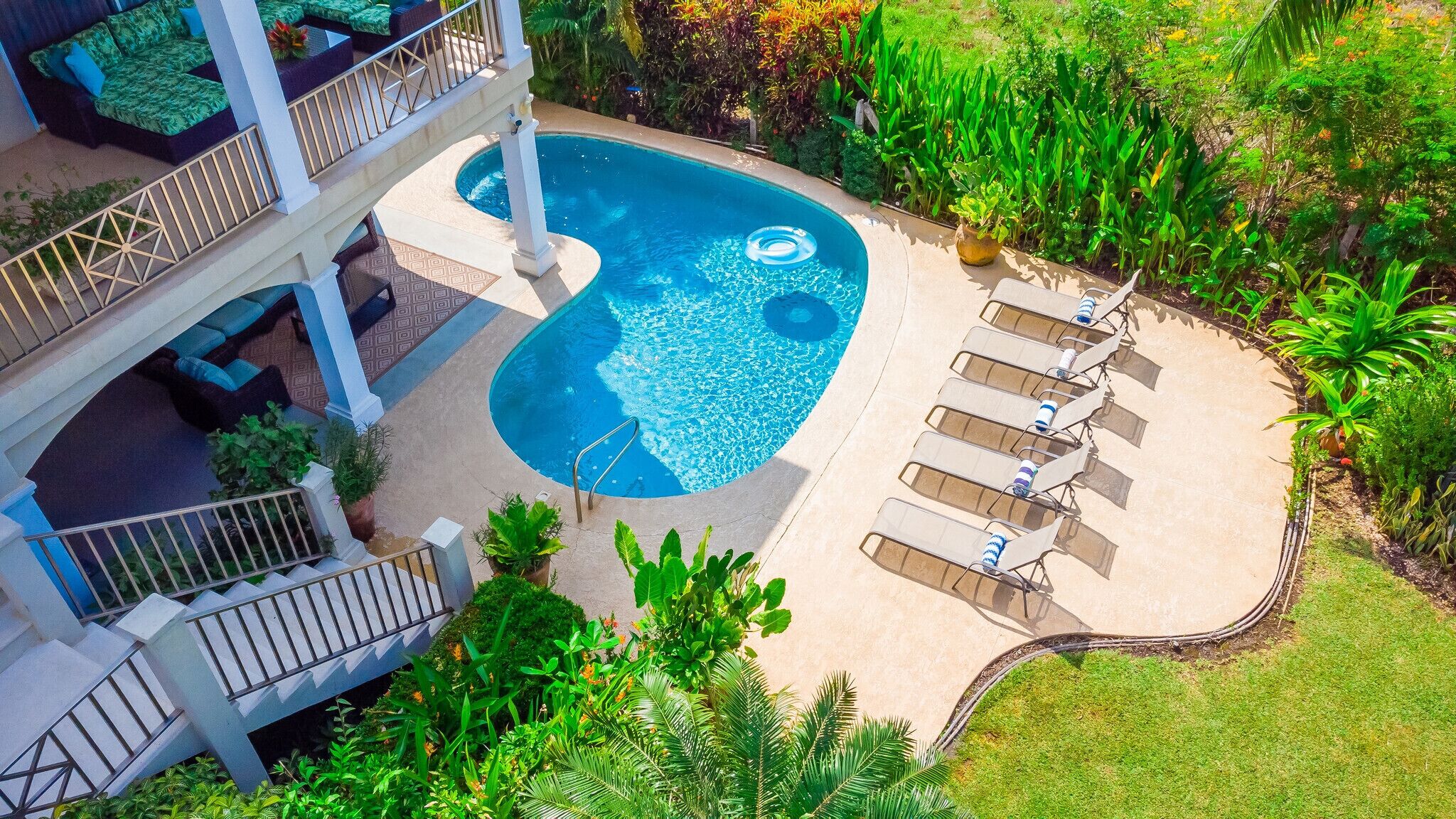 A swimming pool with lounge chairs and a staircase leading to a balcony.