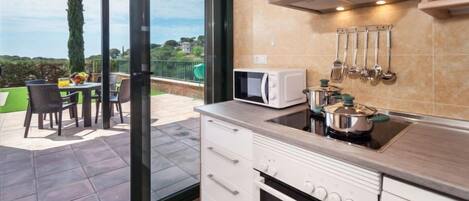 A modern kitchen with a view of the outdoors, including a patio with a table and chairs.
