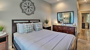 A bedroom with a large bed, a nightstand with a plant, a dresser, and a wall-mounted mirror. - 7 Mi to Dtwn Denver: Arvada Home w/ Patio (Arvada)