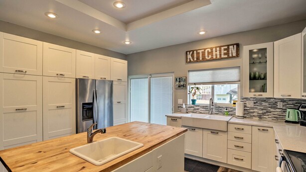 A modern kitchen with white cabinets, a wooden countertop, stainless steel appliances, and a 'KITCHEN' sign on the wall. - 7 Mi to Dtwn Denver: Arvada Home w/ Patio (Arvada)