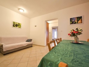 A dining area with a green tablecloth, a sofa, and a vase with flowers. - Apartment Zdenko by Interhome (Ugljan/Kali)