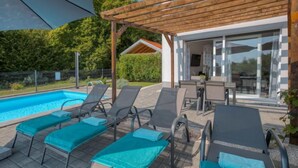 Un espace aménagé au bord de la piscine, avec des chaises longues et une pergola.