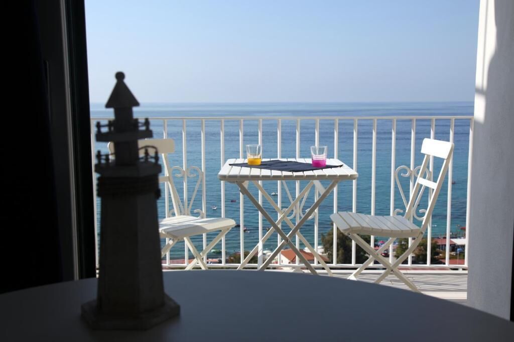 En balkon med et bord og to stole med udsigt over havet.
