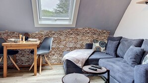 A loft-style room with a dining area, a sofa, and a small round table with remotes. - Eifelhome One nahe Nürburgring by Interhome (Antweiler)