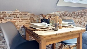 A dining area with a brick wall, a wooden table, and two chairs. - Eifelhome One nahe Nürburgring by Interhome (Antweiler)