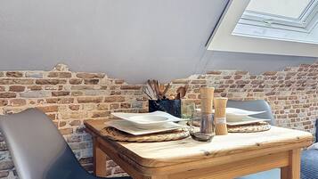 Een eetgedeelte met een bakstenen muur, een houten tafel en twee stoelen.