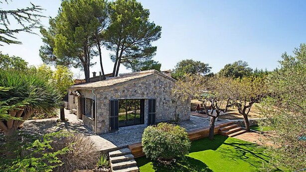 A stone house with a stone staircase leading to a green lawn, surrounded by trees and shrubs. - Can Coll by Interhome (Selva)