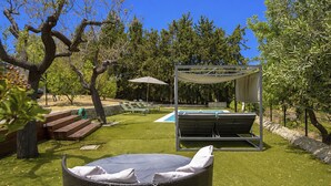 A backyard with a grassy lawn, a pool, lounge chairs, and a pergola. - Can Coll by Interhome (Selva)