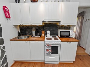 Een koelkast, een magnetron, een vaatwasser, kookgerei, borden en bestek