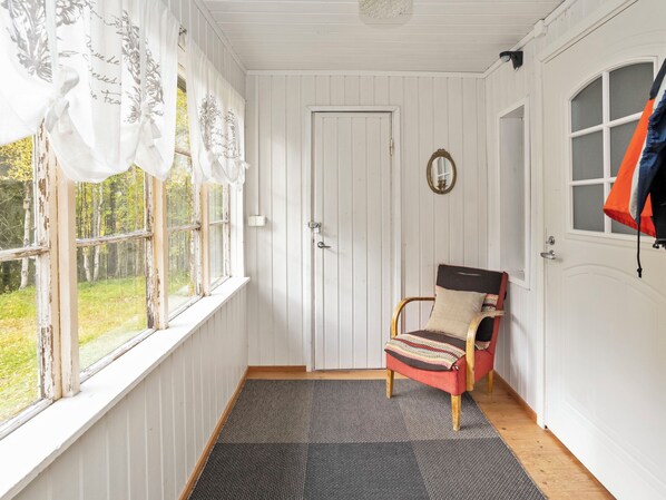 A room with a wooden floor, a door, a chair, and a window with curtains.