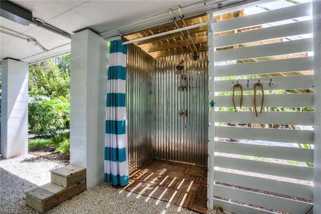 Une pièce dotée d’un plancher en bois, d’un mur en métal et d’une cloison blanche avec des lattes horizontales.