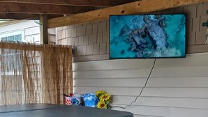 Una vasca idromassaggio con scalini, una TV a muro e un soffitto in legno.