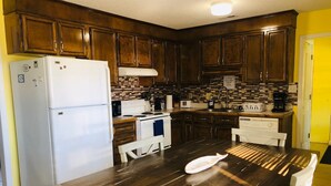 Una cucina con mobili in legno, un frigorifero bianco, un piano cottura e un tavolo da pranzo con sedie.