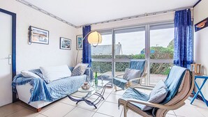 A room with a bed, a chair, a table, and a large window with curtains.