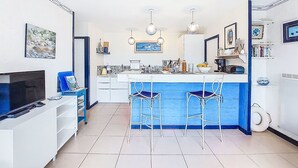 A modern kitchen with a central island, bar stools, and a dining area.