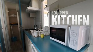 A compact kitchen with a microwave, sink, and a dish rack. - Mobile home in seaside private camp 2 (Sukošan)