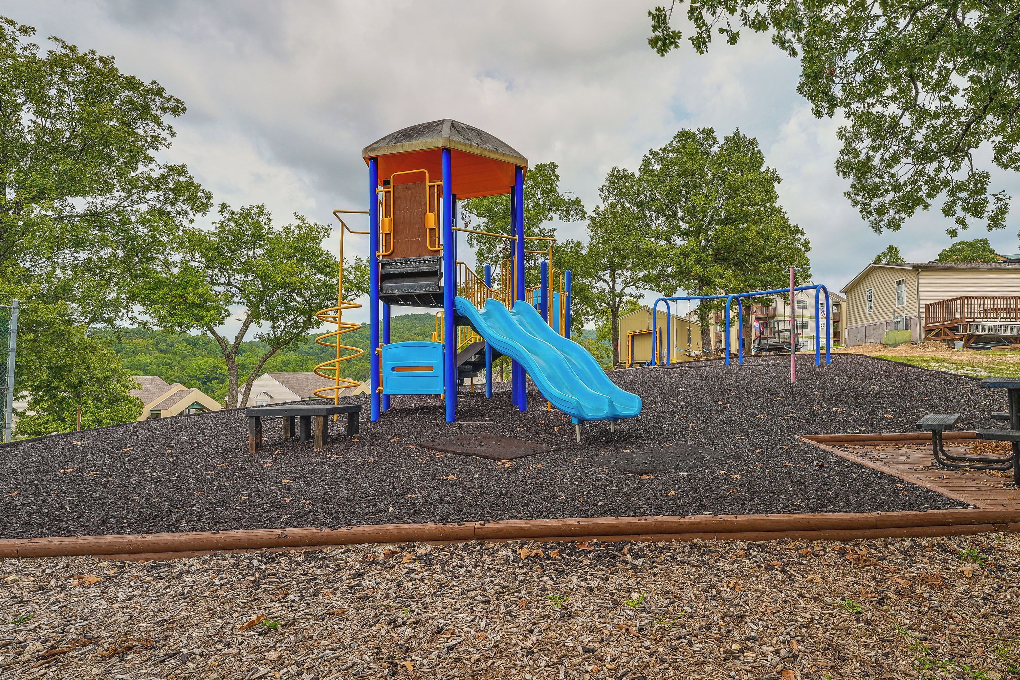 A playground with a slide, climbing structures, and a covered playhouse.