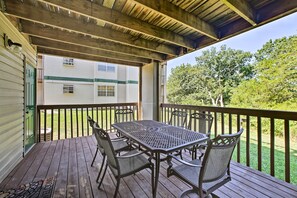 En overdækket terrasse med et bord og stole, med udsigt over en græsplæne og en hvid campingvogn.