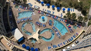 An aerial view of a resort with multiple swimming pools, sun loungers, and umbrellas.