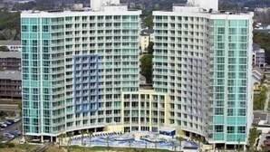 A high-rise hotel with a curved facade, multiple floors, and a parking area in front.