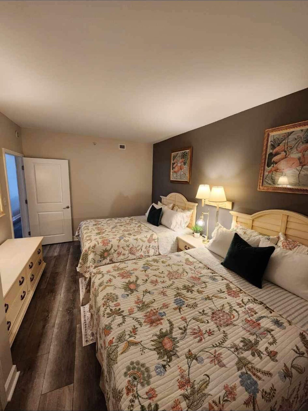 Une chambre avec deux lits, une commode et une porte.