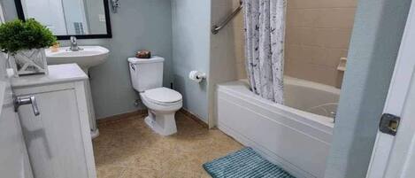 A bathroom with a toilet, sink, and shower area.