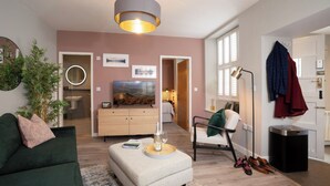 A modern living room with a green sofa, a coffee table, a TV, and a large window with blinds. - Dog friendly apartment with Sky TV by LetMeStay (Ambleside)