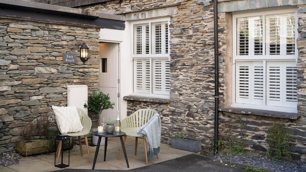 A stone building with a sign reading "Easy Reach". There are two chairs and a small table with a candle and a plant. - Dog friendly apartment with Sky TV by LetMeStay (Ambleside)