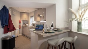 A modern kitchen with a laptop, wine bottle, and glasses on the counter. - Dog friendly apartment with Sky TV by LetMeStay (Ambleside)