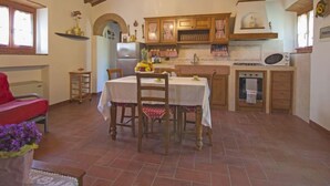 Eine rustikale Küche mit Holzschränken, einem Esstisch mit Stühlen und einem roten Sofa.
