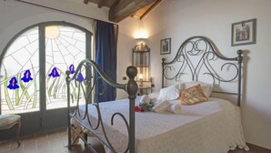 Ein Schlafzimmer mit einem Bett, einem Fenster mit blauen Blumen, einer Wandleuchte und einem Bild an der Wand.