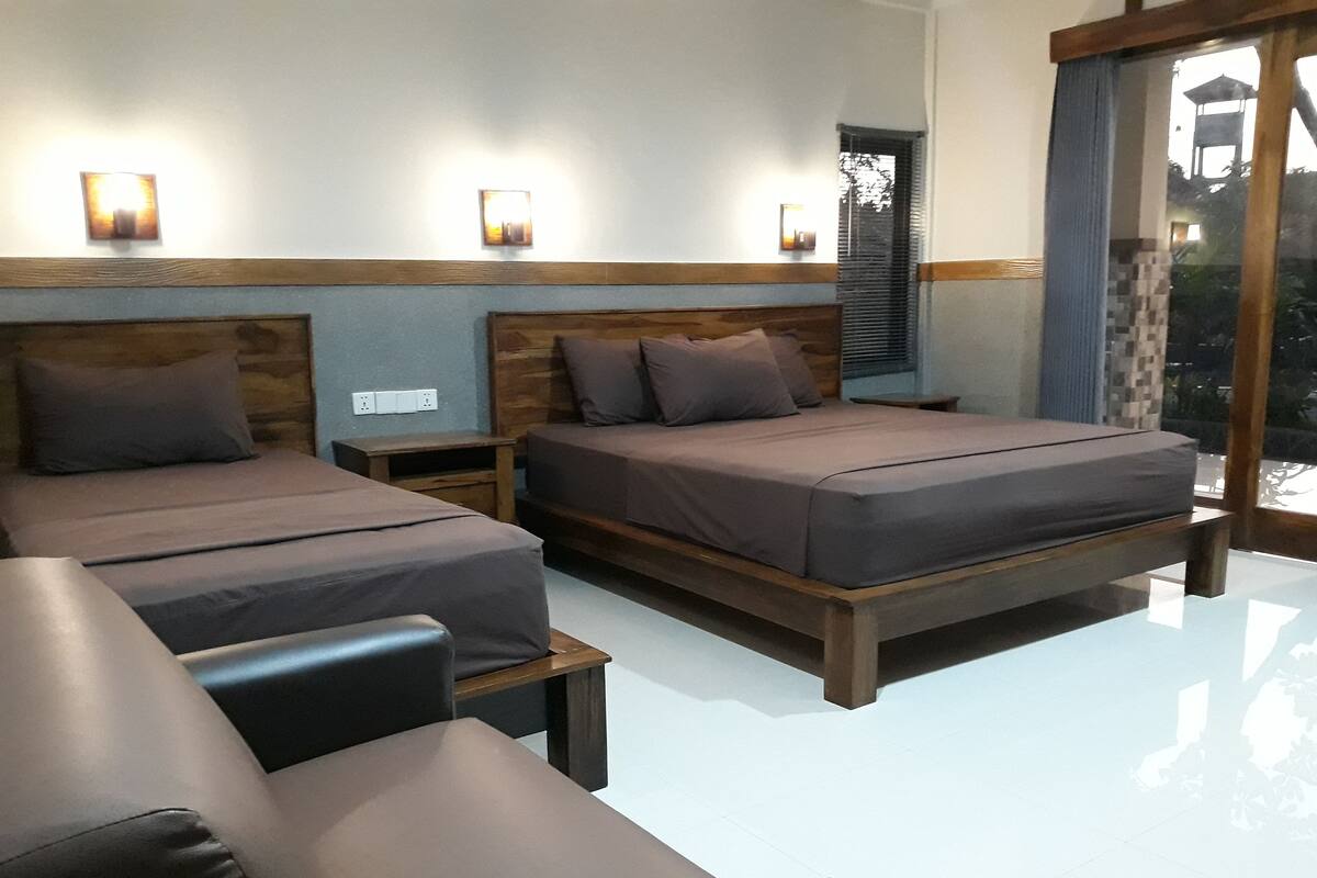 A hotel room with two beds, a small table, and a large window.