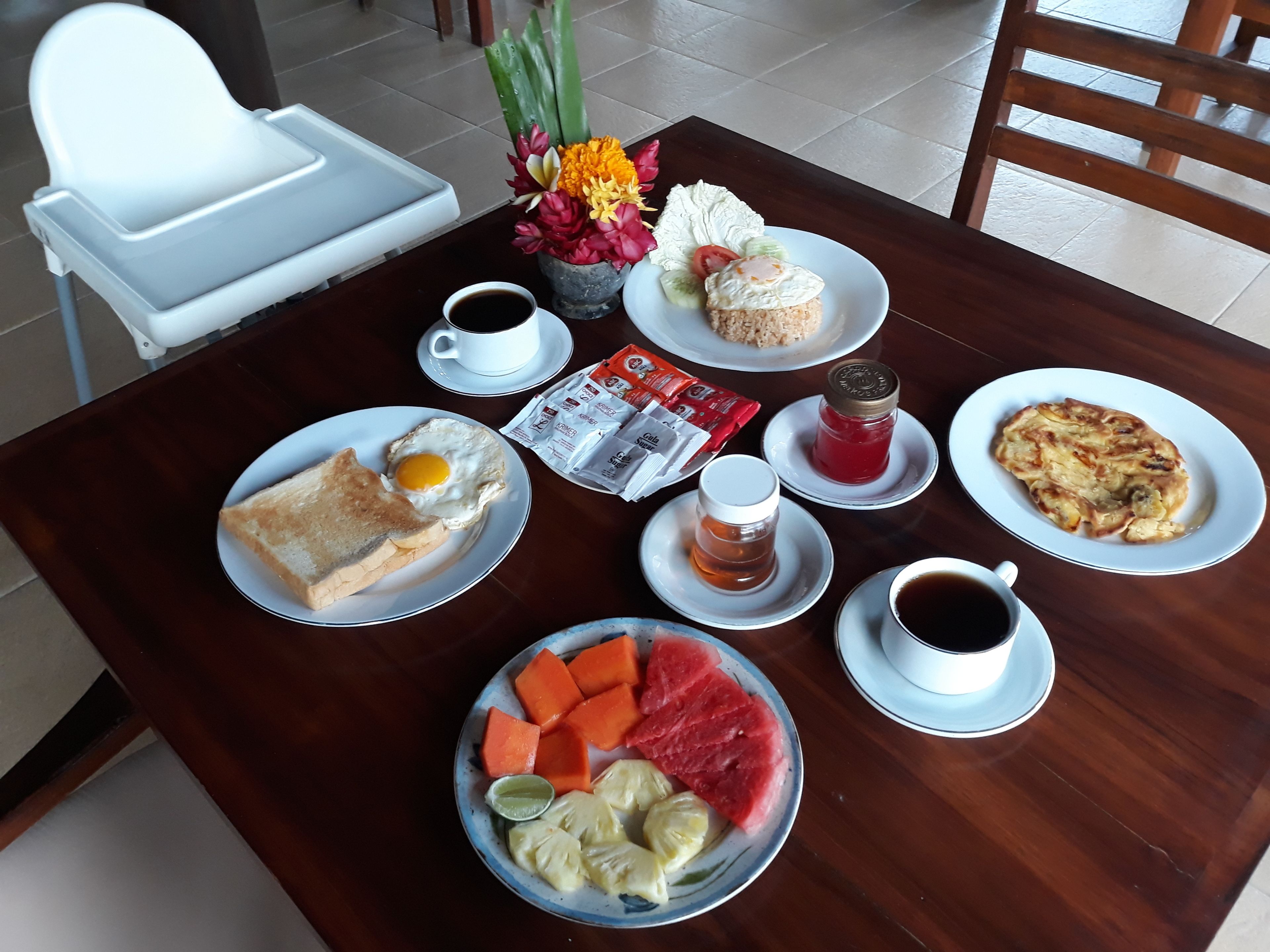A dining table with breakfast items including toast, eggs, and a fruit bowl.