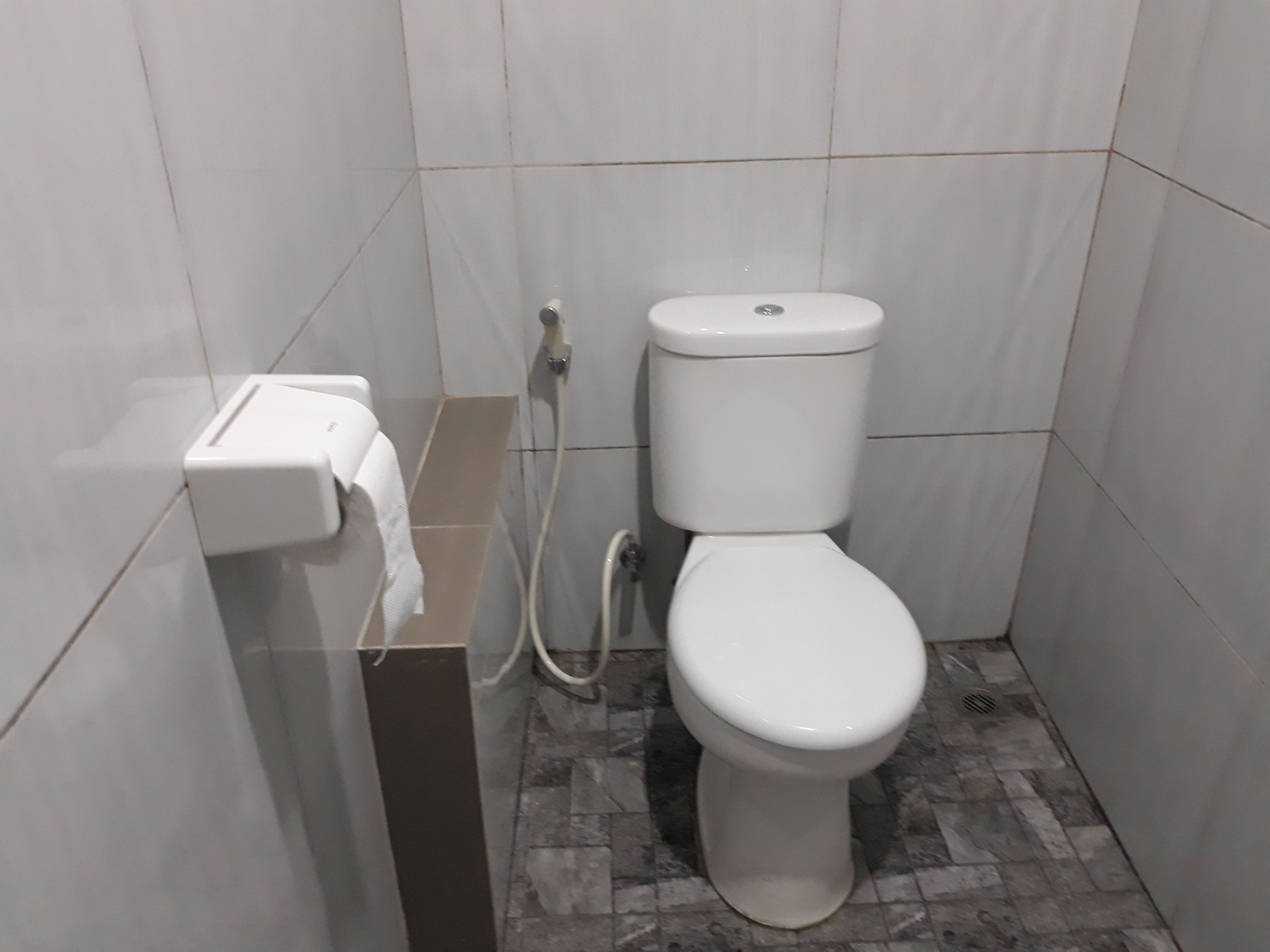 Un baño pequeño y moderno con inodoro, dispensador de toallas de papel y suelo con diseño de mármol.