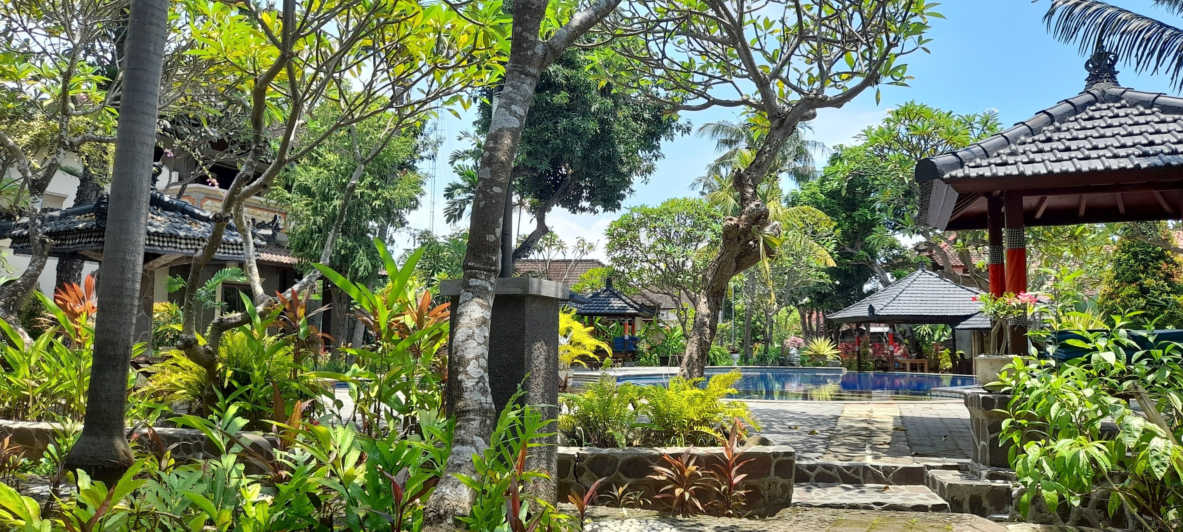 A traditional-style building with a tiled roof, surrounded by lush greenery and a stone pathway.