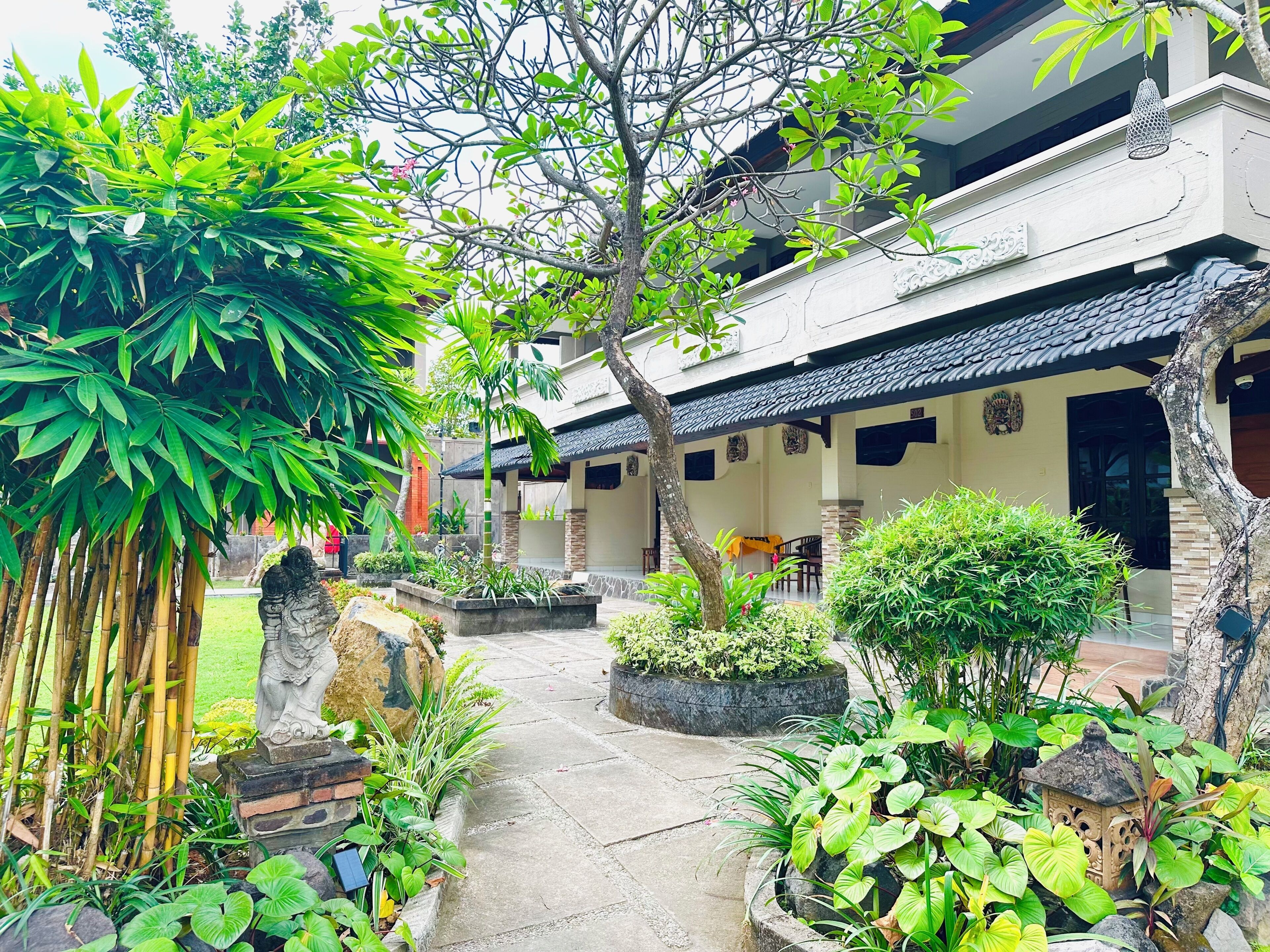 A courtyard with a pathway, a statue, and a building with a tiled roof.