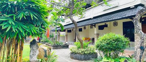 A courtyard with a pathway, a statue, and a building with a tiled roof.