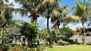 Un jardín tropical con palmeras, un pabellón y un muro de piedra.