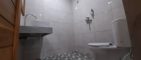 Un baño pequeño y moderno con inodoro, lavamanos y ducha.