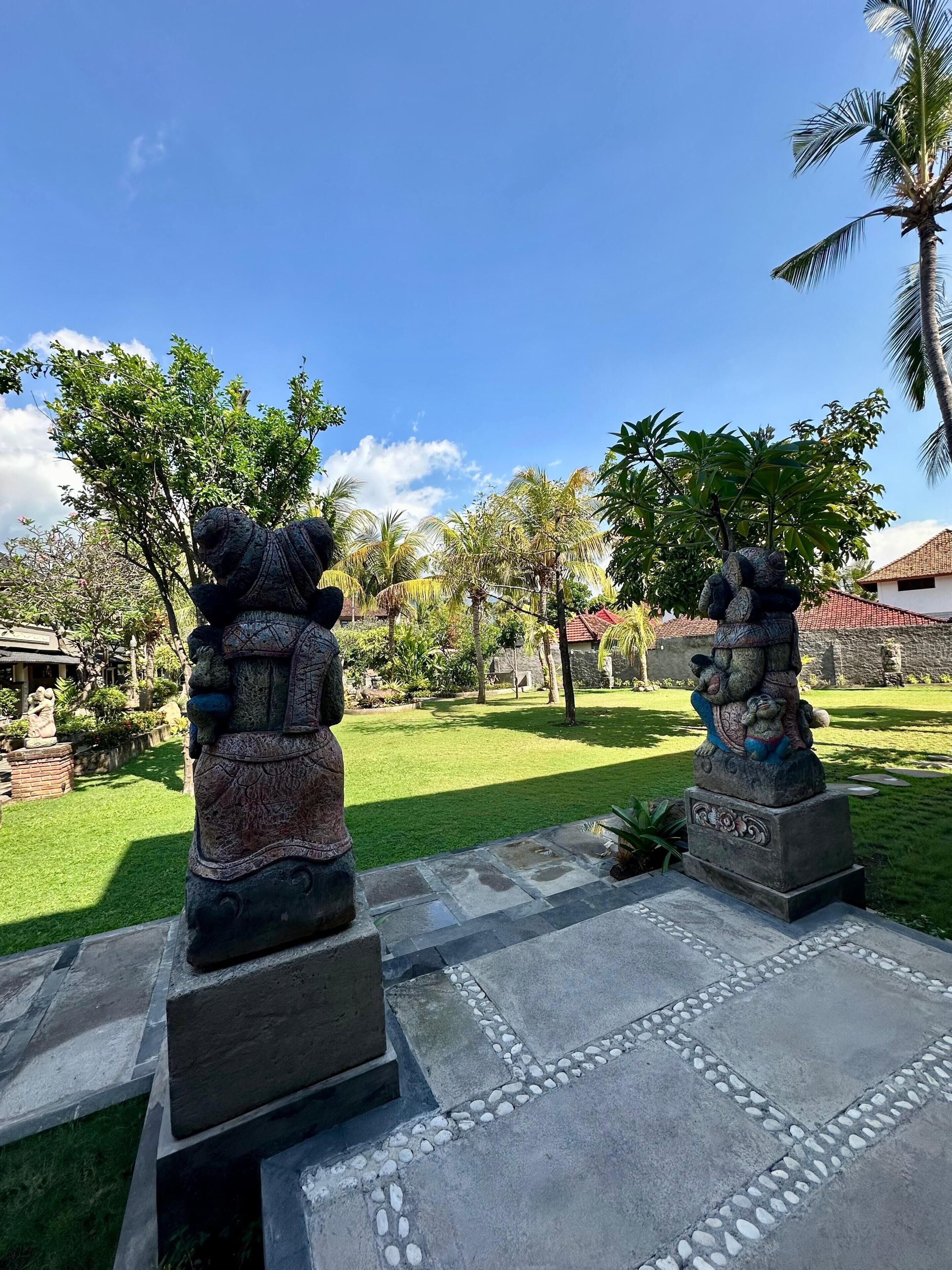 Dos estatuas de piedra en un jardín con cielo despejado.