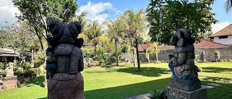 Two stone statues in a garden with a clear sky.