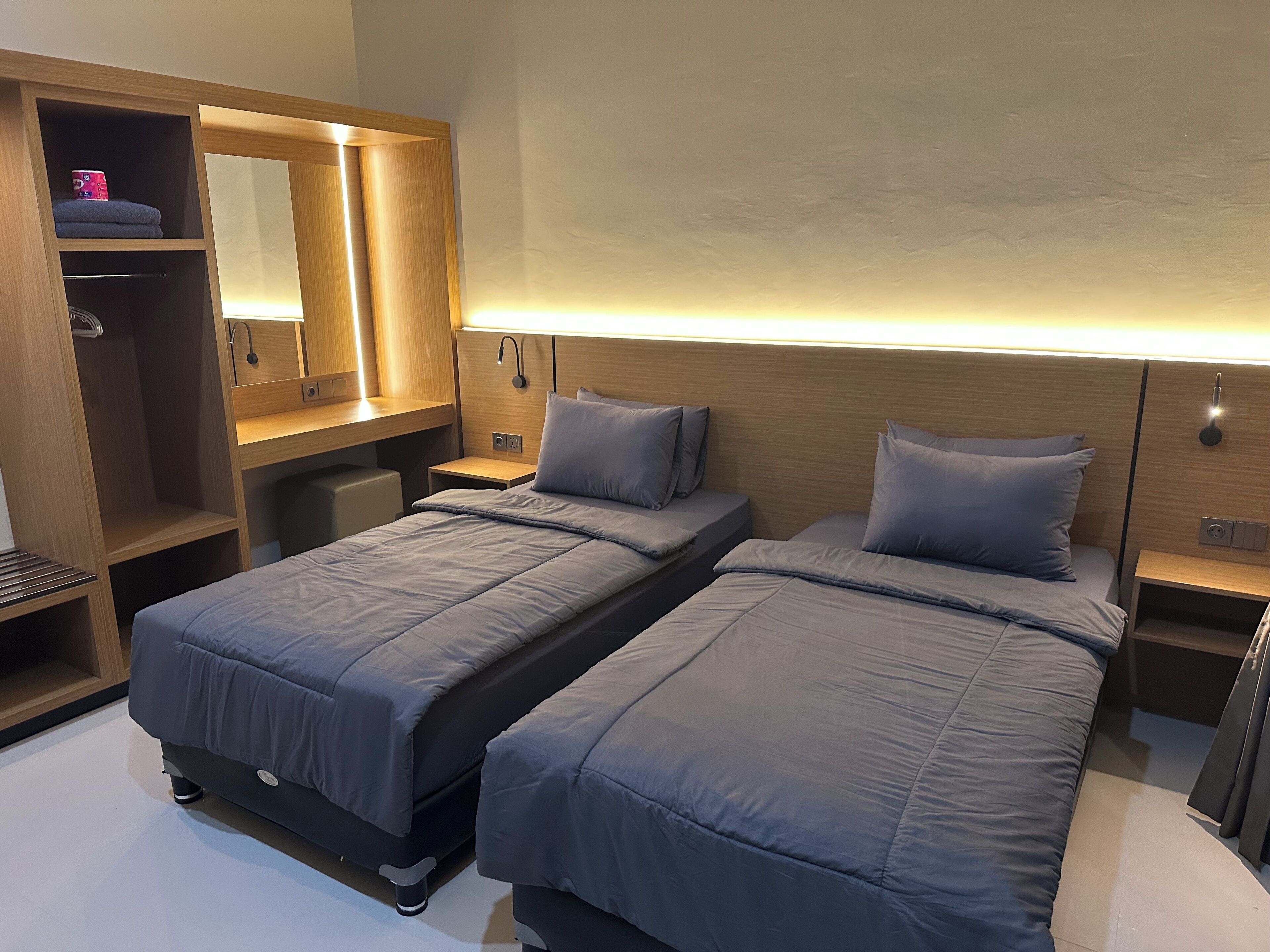 Quarto com duas camas, um guarda-roupa e um espelho.
