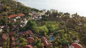 Vista aérea de una zona residencial costera con casas, una playa y una piscina.